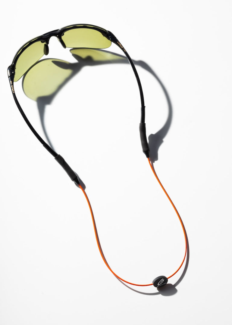 Orange GRAPLRZ sunglass retainers attached to a black pair of sunglasses on a white background
