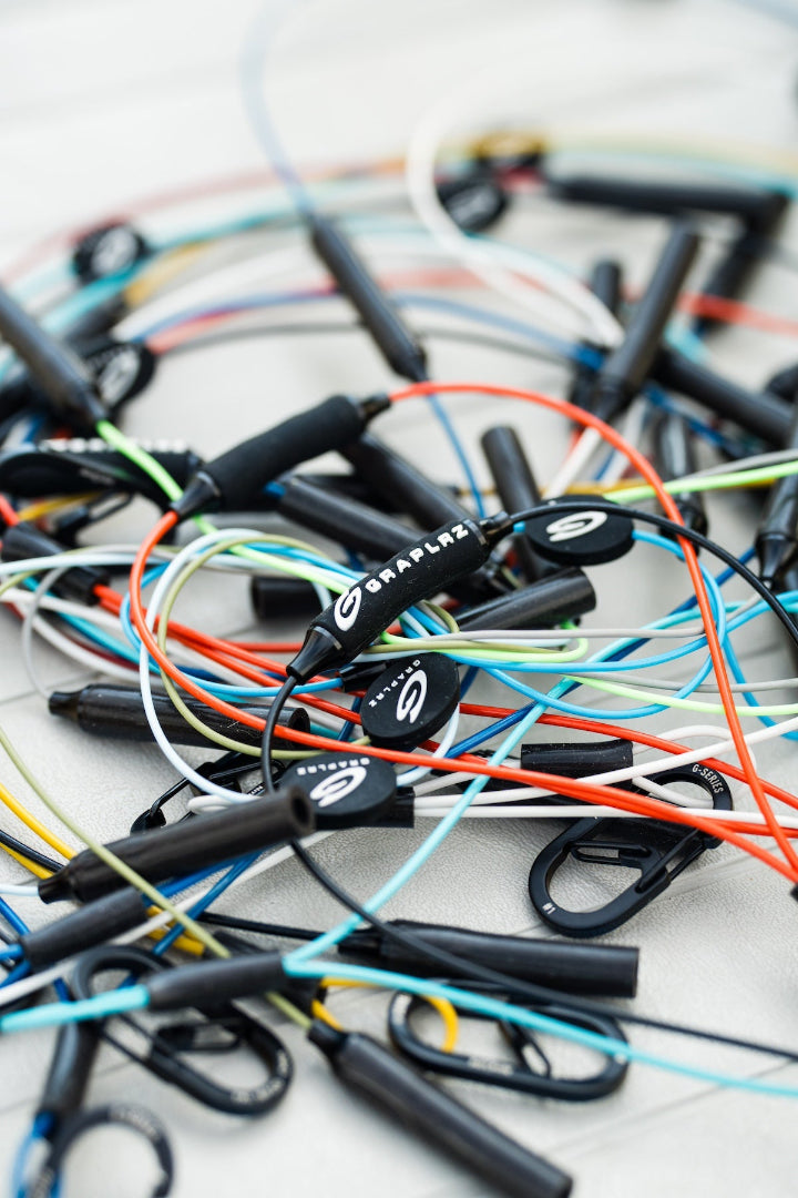 Pile of all different colored GRAPLRZ Verza Mini Utility Lanyards stacked on top of each other on a white background