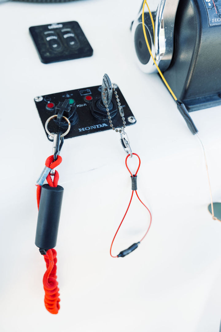 Keys in a boat's ignition clipped to orange GRAPLRZ Verza Mini Utility Lanyard