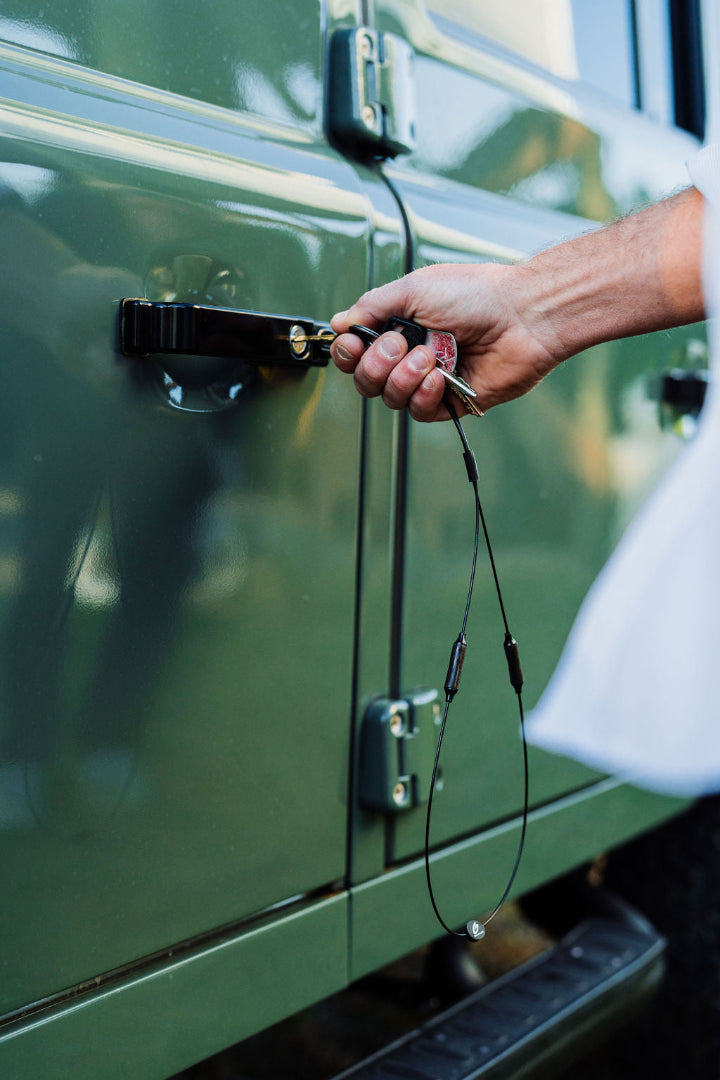 Hand inserting keys attached to GRAPLRZ Verza Mini Utility Lanyard into car door lock