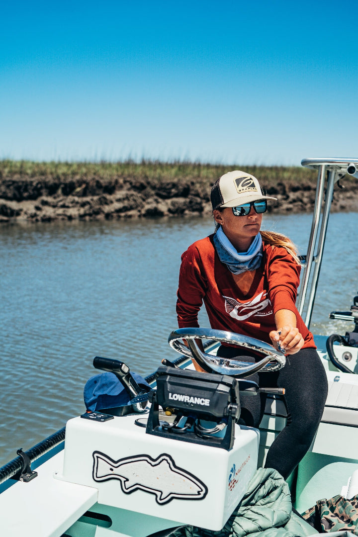 Woman steering a boat wearing a GRAPLRZ hat and shirt