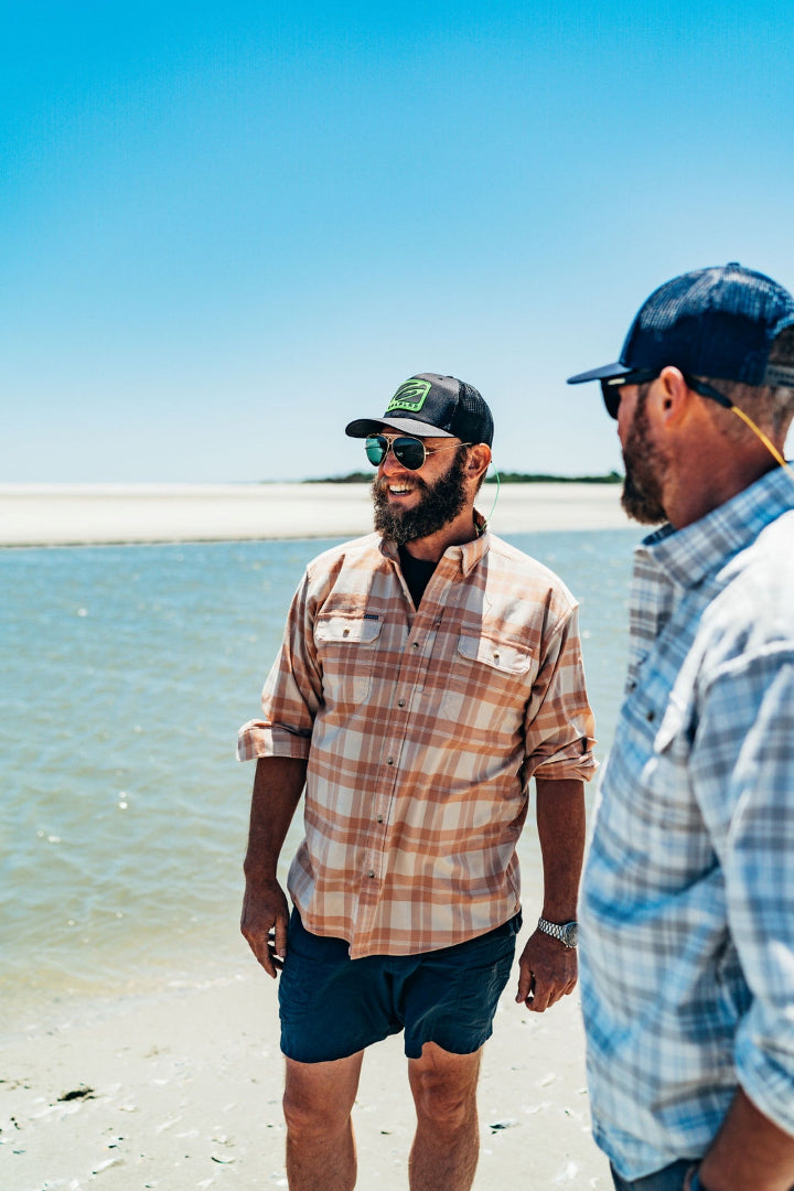 Two men in hats and sunglasses with GRAPLRZ sunglass straps laughing by the ocean